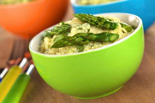 Green asparagus risotto in colorful bowls (Selective Focus, Focus on the asparagus tip in the front)