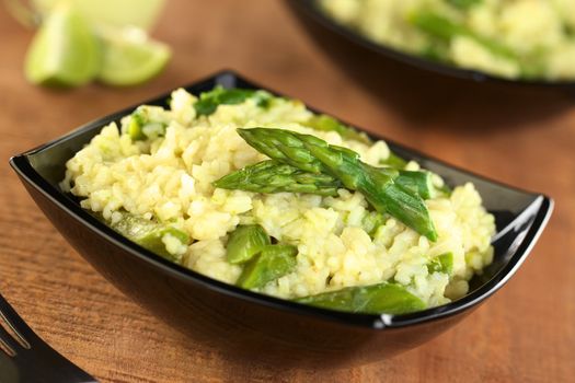 Green asparagus risotto in black bowl (Selective Focus, Focus on the two asparagus tips in the front)