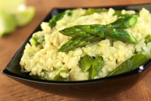 Green asparagus risotto in black bowl (Selective Focus, Focus on the two asparagus tips in the front)