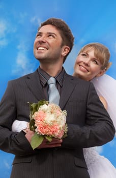 groom and the bride stand against the blue sky