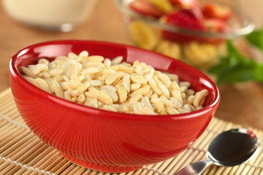 Puffed rice cereal with fruits and milk in the back (Selective Focus, Focus in the middle of the bowl)