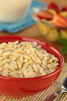 Puffed rice cereal with fruits and milk in the back (Selective Focus, Focus in the middle of the bowl)