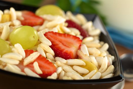 Puffed rice cereal with fresh strawberries, bananas and grapes (Selective Focus, Focus on the front edge of the strawberry in the middle of the image)