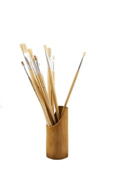 Artistic painting brushes in wooden pot over white backdrop