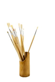 Artistic painting brushes in wooden pot over white backdrop