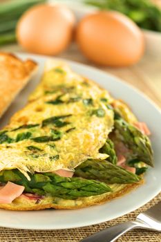 Green asparagus and ham omelet with eggs in the back (Selective Focus, Focus on the asparagus head in the front)