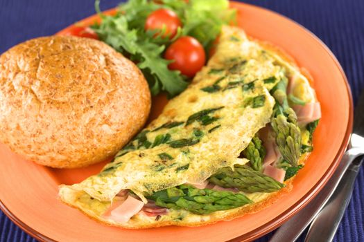 Green asparagus and ham omelet with wholewheat bun and salad on a plate (Selective Focus, Focus on the second asparagus head)