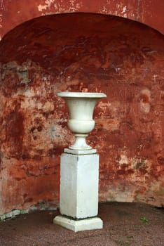 Marble vase on backdrop of defaced ancient wall with carved graffiti