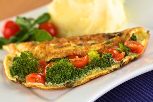 Broccoli and tomato omelette with mashed potato and watercress salad (Selective Focus, Focus on the broccoli floret in the front)