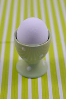 White breakfast egg in the egg cups on the green and white striped background