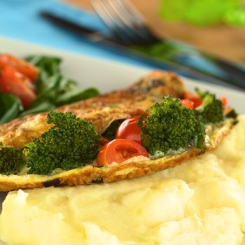 Broccoli and tomato omelette with mashed potato (Selective Focus, Focus on the broccoli floret and tomato piece on the left)