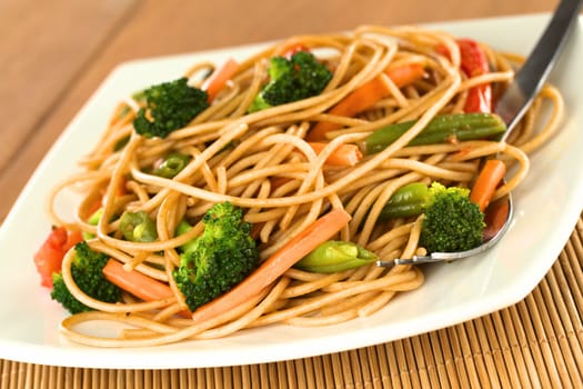 Vegetable and wholewheat spaghetti stir fry with fork (Selective Focus, Focus on the vegetables in the front)
