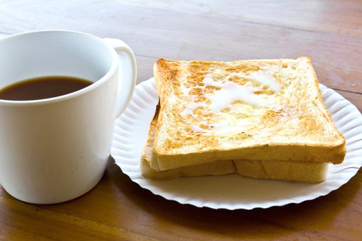 Coffee cup and Pour the milk toast on the wooden table