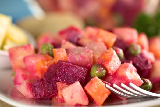 Russian beetroot salad made of beetroot, potato, carrot, pea and a mayonnaise dressing (Selective Focus, Focus on the pea in the front and the beetroot beside it) 