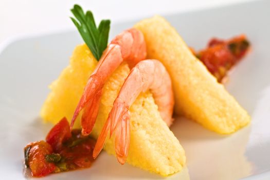 Polenta slices with cooked shrimp and Colombian hogao sauce (Selective Focus, Focus on the right part of the tail of the first shrimp)