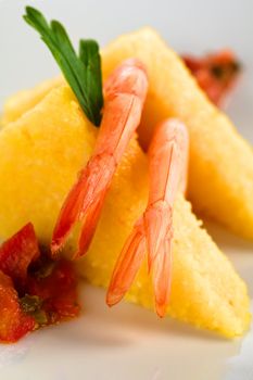 Polenta slices with cooked shrimp and Colombian hogao sauce (Selective Focus, Focus on the middle part of the tail of the right shrimp)