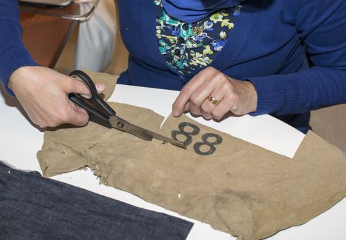 adult woman dressed in blue making clothes in workshop