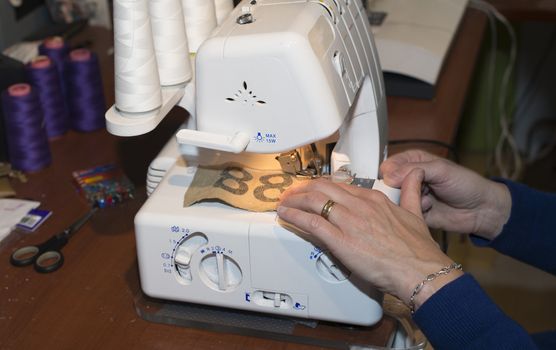 adult woman dressed in blue making clothes in workshop