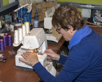 adult woman dressed in blue making clothes in workshop