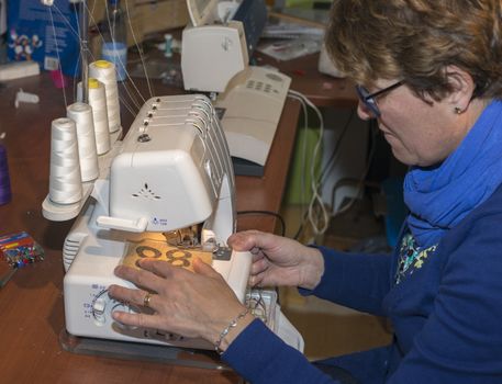 adult woman dressed in blue making clothes in workshop