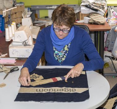 adult woman dressed in blue making clothes in workshop