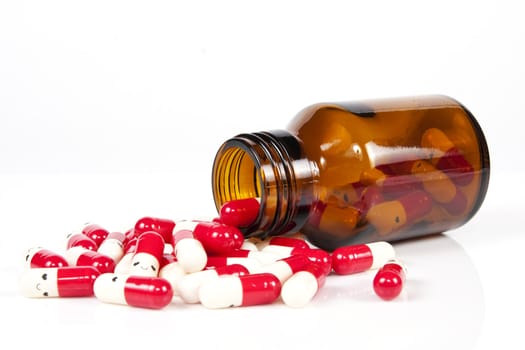 Open happy pill bottle with medicine spilling out of it isolated on white