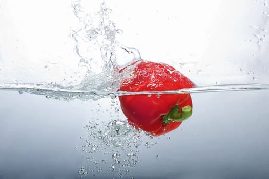 Fresh Red Bell Pepper splashing into water