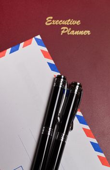 executive planner with white envelopw and pens in portrait orientation