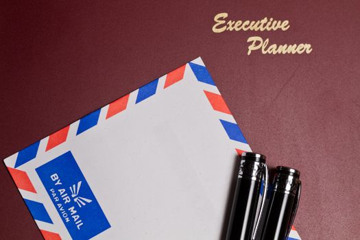 executive planner with white by air mail envelopw and pens  in landscape orientation