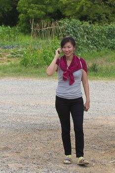 Young woman talking on a mobile against a plant background