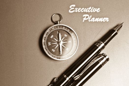an executive planner with simple compass and two pens in sepia tone