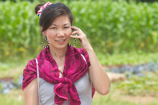 Young woman talking on a mobile against a plant background