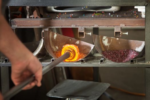 Iron rod with molten glass placed in colored stones