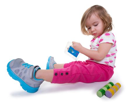 Toddler girl with colorful chalks in her hands getting ready for activity time, isolated on white.