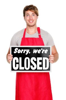Business owner / employee showing closes sign. Man wearing red apron smiling happy. Caucasian male model.