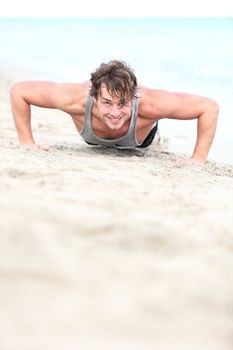 sport man training push ups on beach. Young hand some caucasian fitness model in his twenties working out outside on beach.