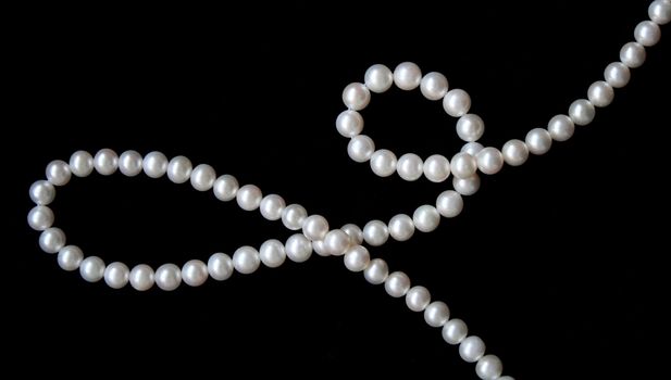 White pearls on the black velvet background 