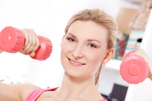 Young beautiful woman with dumbbells working out at home