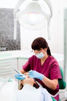 Female dentist working on patient in modern dental cabinet