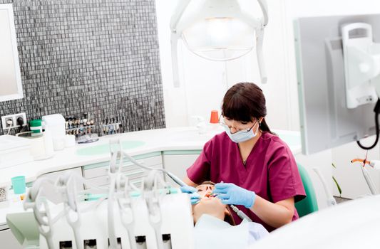 Female dentist working on patient in modern equipped cabinet