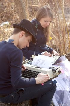 Young man typing on a typewriter in the park