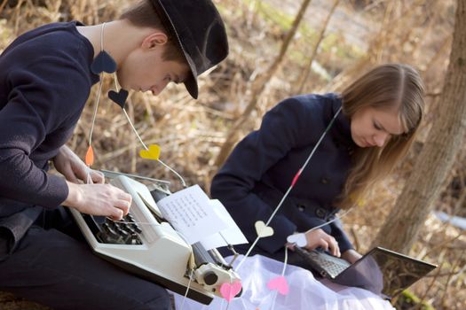 young man and woman typing on a typewriter in the park