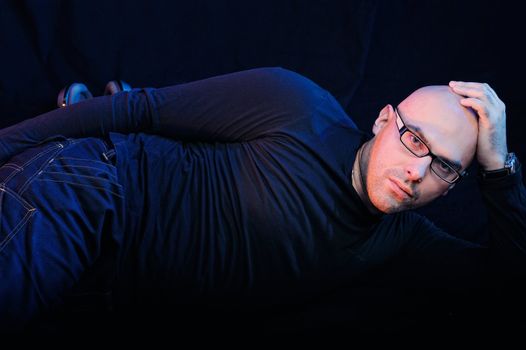 Man in black lying on the floor. Studio-style portrait