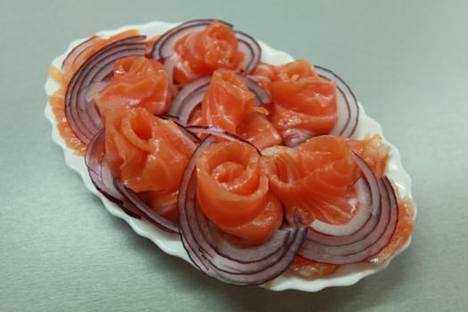 Slices of salmon with red onion on a plate