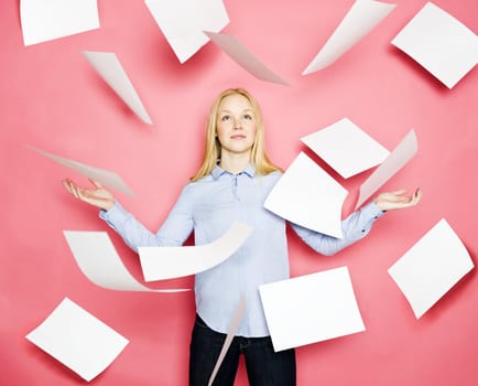 Businesswoman with flying papers on pink background