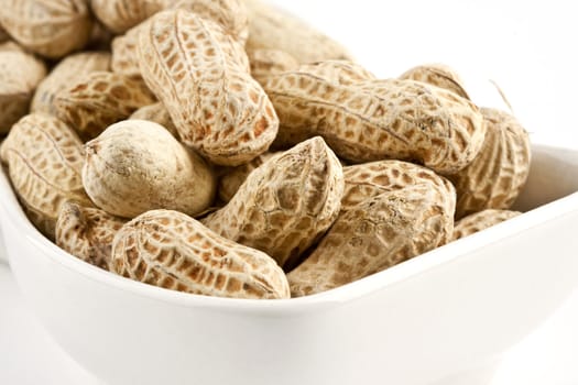 Peanut in shell snack on white plate, shallow DOF focus in the middle.