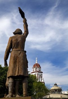 Statue of Miguel Hidalgo in Public Park with Churches in Backgroud, Tlaquepaque, Guadalajara, Mexico.  Father Hidalgo was one of the heroes of the Mexican War of Independence in the early 1800s.