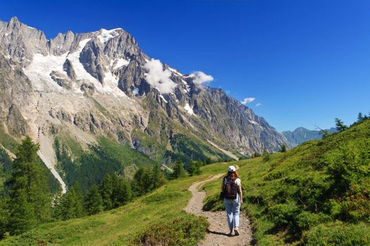 hiker in action in Ferret valley with Mont Blanc massif on background