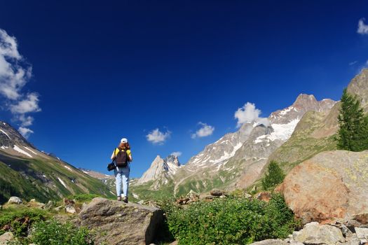 young woman stands on a rocks in Italian Alps