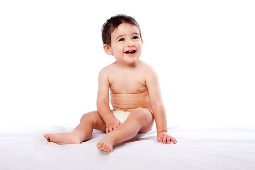 Cute happy smiling teething baby toddler sitting in diaper, childhood concept.